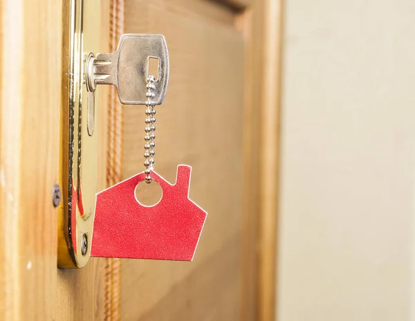 Uma chave em uma fechadura com ícone de casa nele — Fotografia de Stock