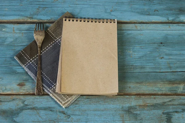 Alter Löffel und braunes Notizbuch auf bunter Serviette — Stockfoto
