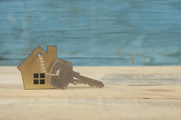 Símbolo de la casa con llave de plata sobre fondo de madera vintage —  Fotos de Stock