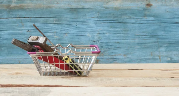 La cesta del supermercado tiene herramientas sobre fondo de madera . —  Fotos de Stock