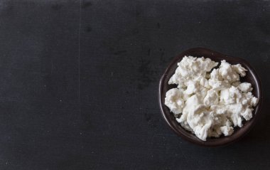 ahşap bir masa üzerinde bir kase taze peynir. 