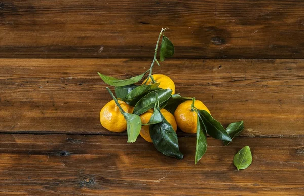 Orange mandarine fraîche avec des feuilles vertes sur fond bois — Photo