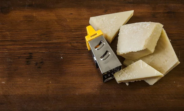 Queso parmesano rallado y rallador sobre fondo de madera — Foto de Stock