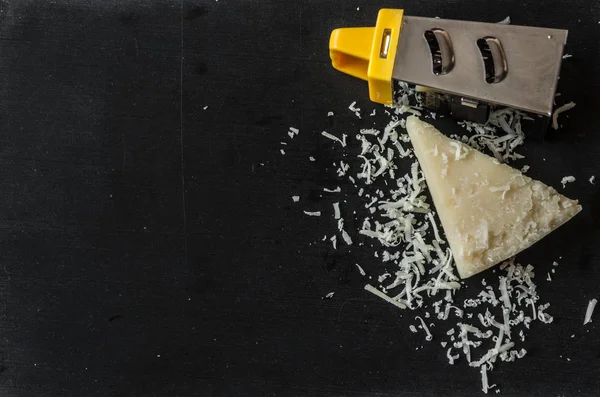 Queijo parmesão ralado e ralador em fundo de madeira — Fotografia de Stock