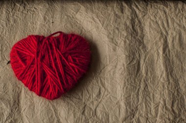 Kırmızı kalp şekli sembolü yün kağıt arka plan üzerinde yapılan. 
