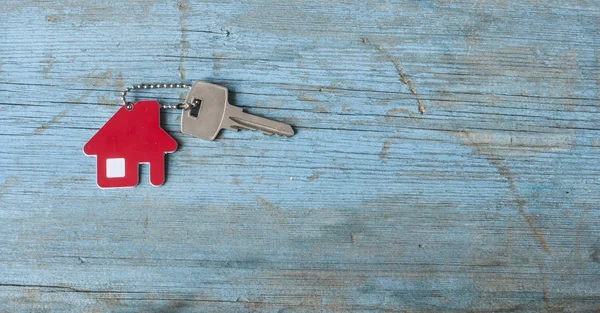 Klíč s ikonu domečku na dřevěné pozadí — Stock fotografie