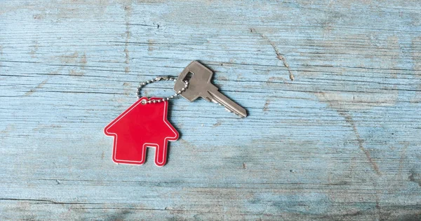 Key with house icon on wooden background — Stock Photo, Image