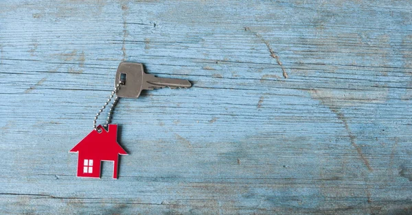 Chave com ícone da casa no fundo de madeira — Fotografia de Stock