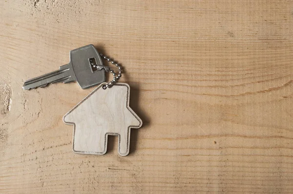 Chave com ícone da casa no fundo de madeira — Fotografia de Stock