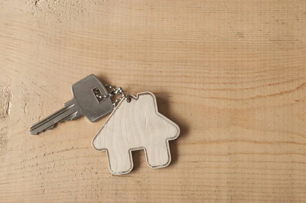 Schlüssel mit Haussymbol auf Holzgrund — Stockfoto