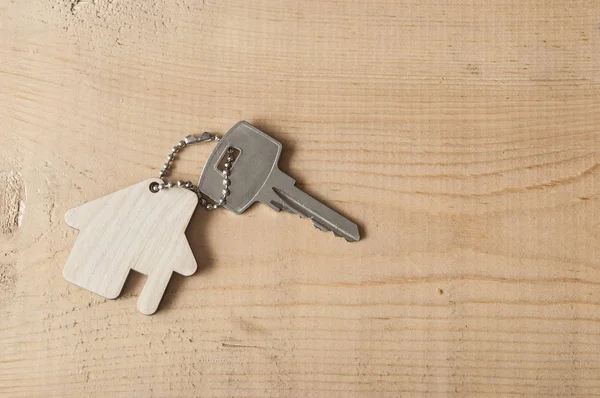 Llave con icono de la casa sobre fondo de madera — Foto de Stock