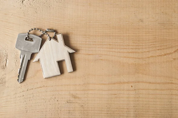 Nyckel med hussymbol på trä bakgrund — Stockfoto