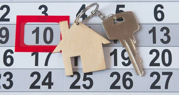 Een huis sleutel op een kalender achtergrond — Stockfoto