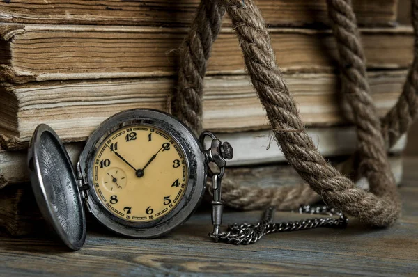 Oude boeken met pocket klok op een houten tafel — Stockfoto