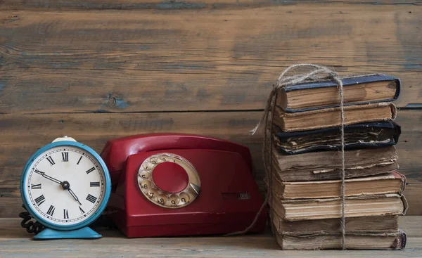 Старые часы на старом деревянном столе со стопкой книг — стоковое фото