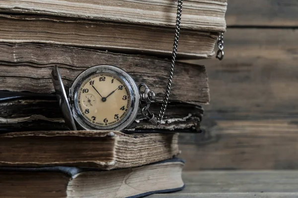 Ahşap bir masa üzerinde cep saati ile eski kitaplar — Stok fotoğraf