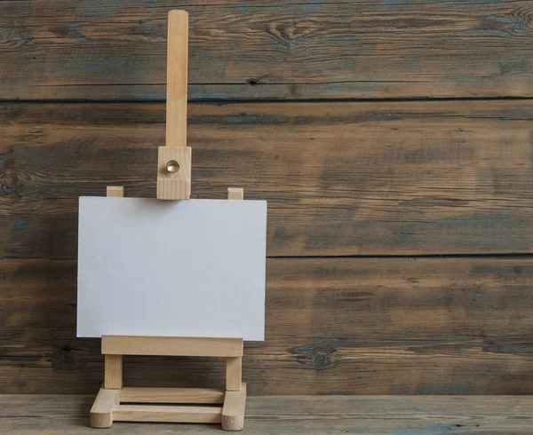 Paleta de cavalete aquarelas e pincéis com tela branca vazia — Fotografia de Stock