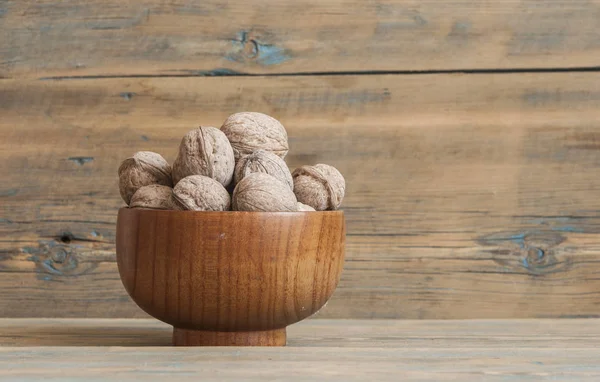 Walnuts in bowl on wooden table — Stock Photo, Image