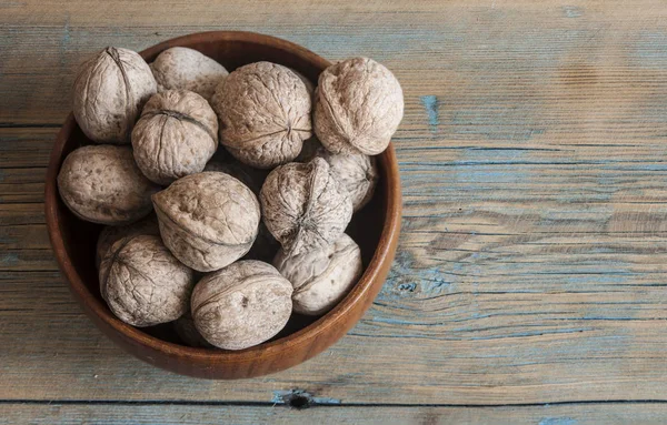 Walnuts in bowl on wooden table — Stock Photo, Image