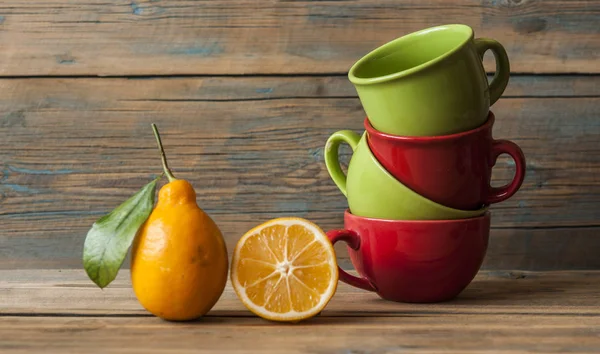 Frische reife Zitronen und bunte Teetasse — Stockfoto