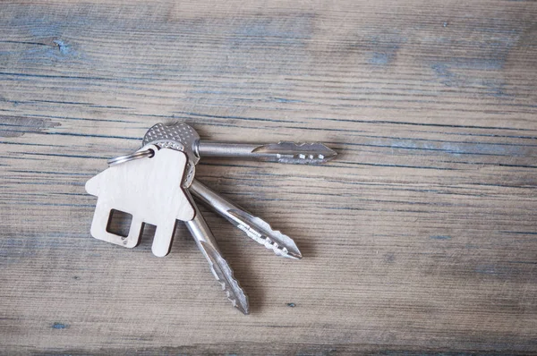 Sleutel met huisje op houten achtergrond — Stockfoto