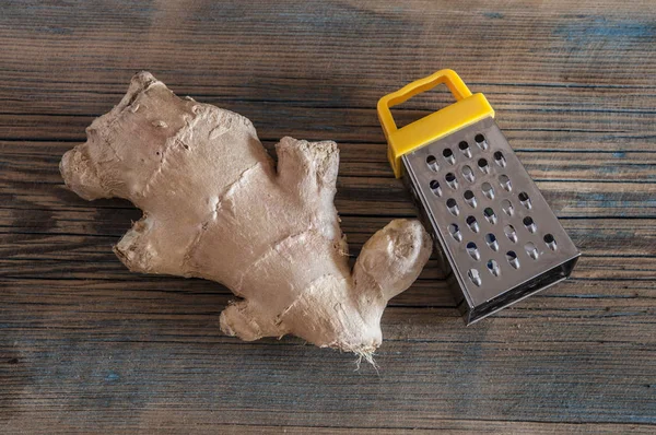 Rallador de acero y raíz de jengibre en mesa de madera — Foto de Stock