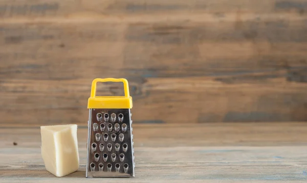 Çelik rende ve ahşap tahta üzerinde peynir — Stok fotoğraf