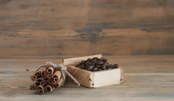 Montón de granos de café, palitos de canela en madera vieja . — Foto de Stock