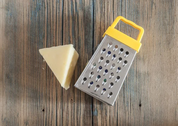 Stalen rasp en kaas op houten plank — Stockfoto