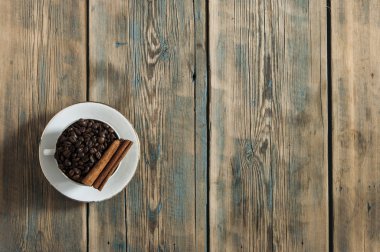 Kahve çekirdekleri ve ahşap zemin üzerine kahve fincanı