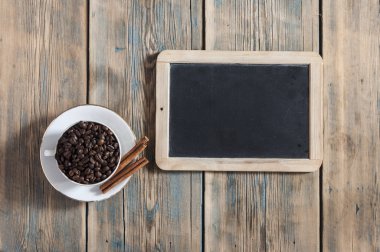 Kahve çekirdekleri ve ahşap zemin üzerine kahve fincanı