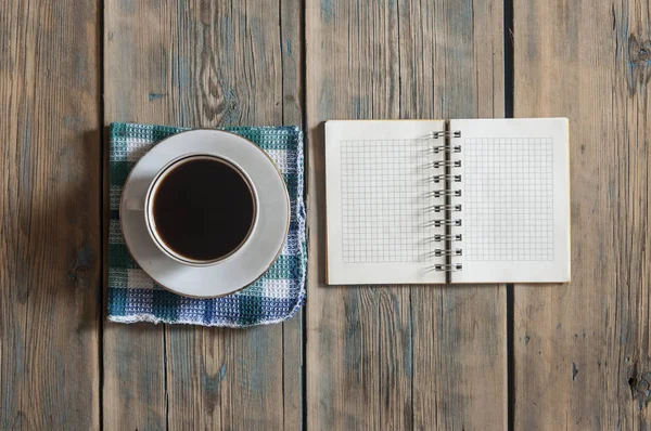 Vista superior de la taza de café expreso y libro de notas en blanco en ta de madera — Foto de Stock