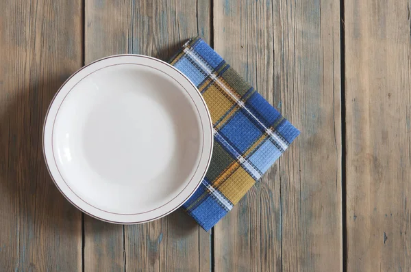 Plato blanco en blanco sobre fondo de madera. — Foto de Stock