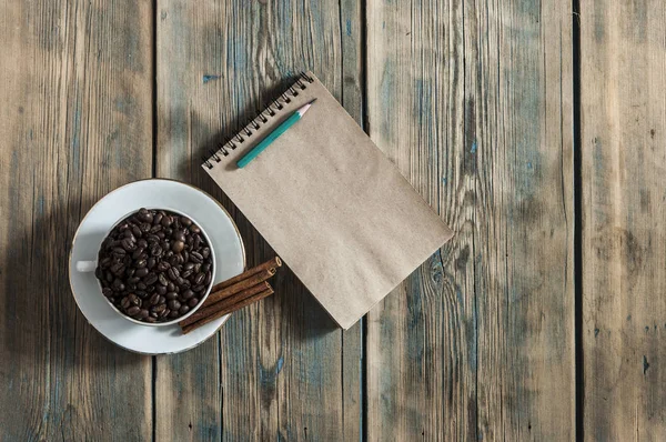 Café en grains et tasse à café sur fond en bois — Photo