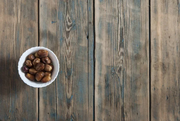 Bowl of pitted dates isolated on a old wooden table, top view — Stock Photo, Image