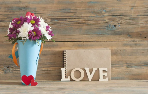 Woord liefde, bloemen en houten achtergrond — Stockfoto