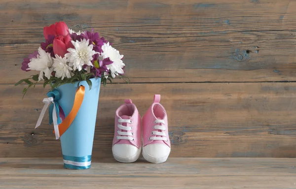 Hermosas flores frescas de primavera y zapatos para niños en una madera — Foto de Stock