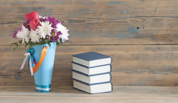 Beautiful fresh spring flowers with stack of books on a table — Stock Photo, Image