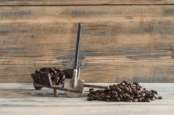 Granos de café tostados pala fondo de madera — Foto de Stock