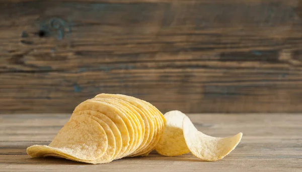 Gyllene naturliga potatischips på ett gammalt träbord — Stockfoto