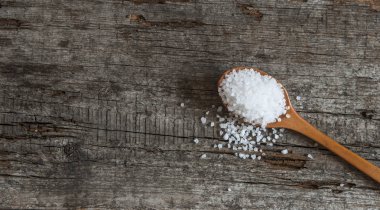 Ahşap arka plan üzerinde deniz tuzu kaşıkla