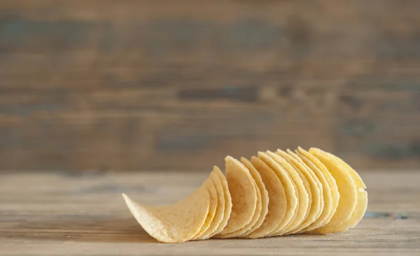 Gyllene naturliga potatischips på ett gammalt träbord — Stockfoto