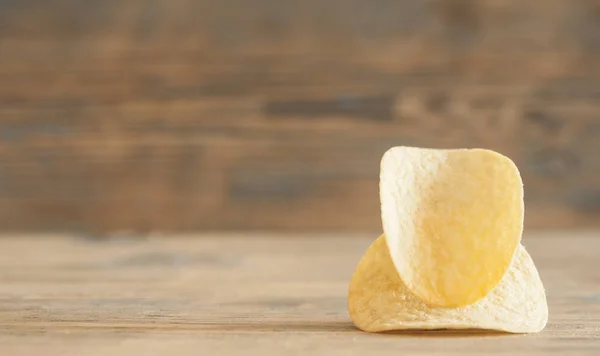 Gyllene naturliga potatischips på ett gammalt träbord — Stockfoto