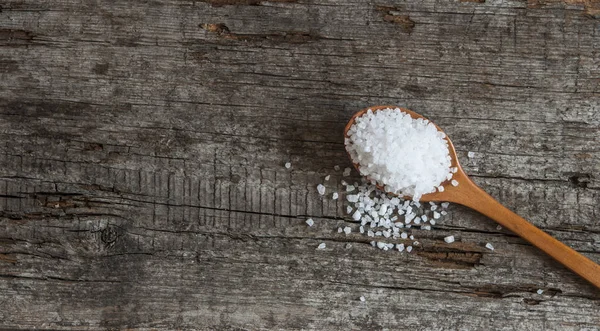 Cuchara con sal marina sobre fondo de madera — Foto de Stock