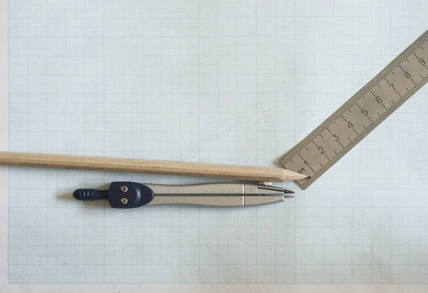 pencil, compass and rulers on graph paper background