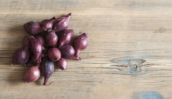 Red onions on a wooden table. Rough texture of untreated wood. — Stock Photo, Image