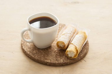 Kahveli tatlı atıştırmalık ve ahşap arka planda waffle tüpleri.