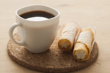 Kahveli tatlı atıştırmalık ve ahşap arka planda waffle tüpleri.