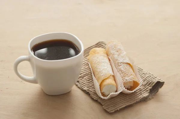 Sött mellanmål med kaffe och våffelrör på trä bakgrund — Stockfoto