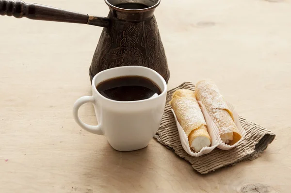 Sött mellanmål med kaffe och våffelrör på trä bakgrund — Stockfoto